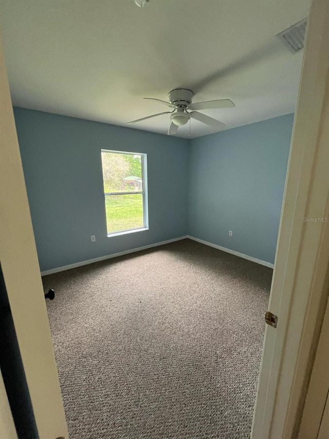 carpeted spare room featuring ceiling fan, baseboards, and visible vents