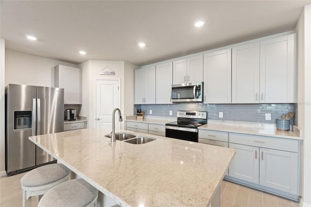 kitchen with tasteful backsplash, light stone counters, appliances with stainless steel finishes, a sink, and a kitchen breakfast bar
