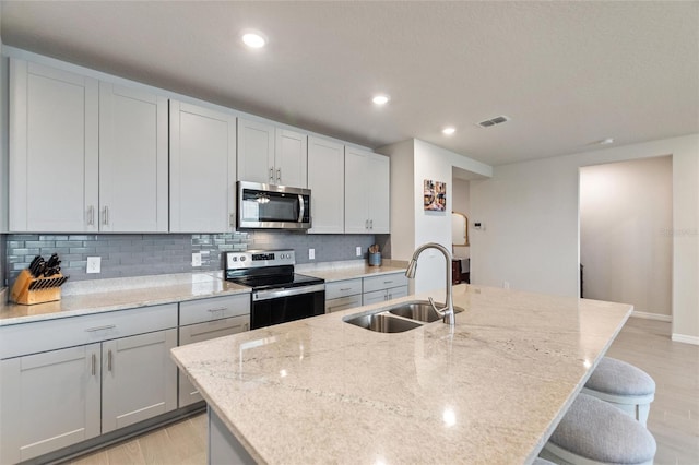 kitchen featuring visible vents, stainless steel appliances, light wood-style floors, and a sink