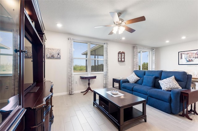 living room with a textured ceiling, baseboards, light wood-type flooring, recessed lighting, and a ceiling fan