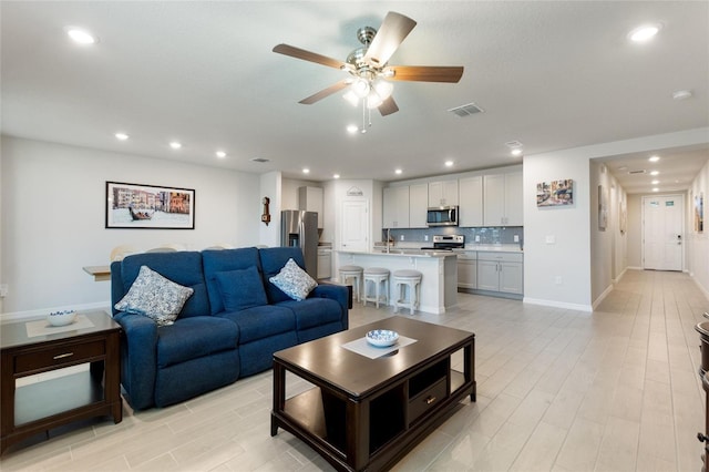living room with visible vents, a ceiling fan, light wood finished floors, and recessed lighting