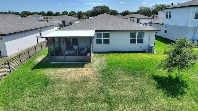 back of house featuring a sunroom, a lawn, a fenced backyard, and roof with shingles