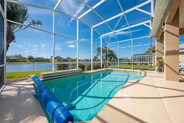 outdoor pool with glass enclosure, a water view, and a patio