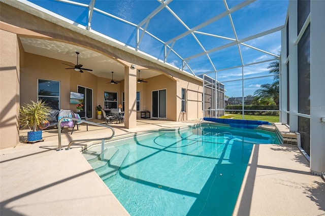 pool featuring a patio area, a ceiling fan, and glass enclosure