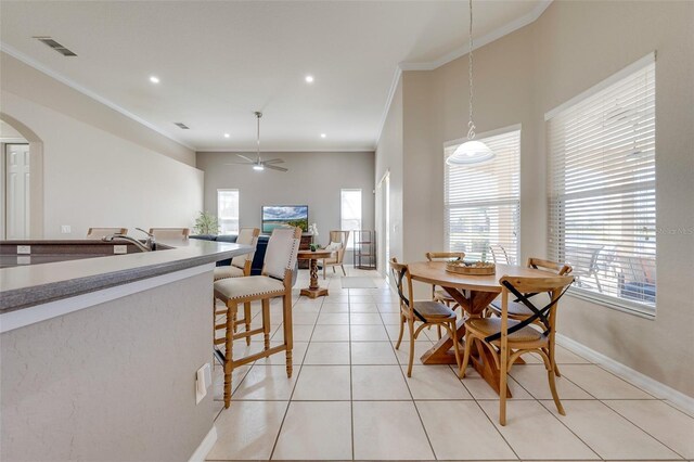 dining area with arched walkways, baseboards, visible vents, crown molding, and light tile patterned floors