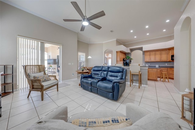 living area with a ceiling fan, crown molding, light tile patterned floors, arched walkways, and baseboards