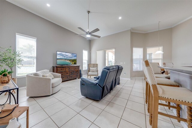 living room with ceiling fan, a wealth of natural light, ornamental molding, and baseboards