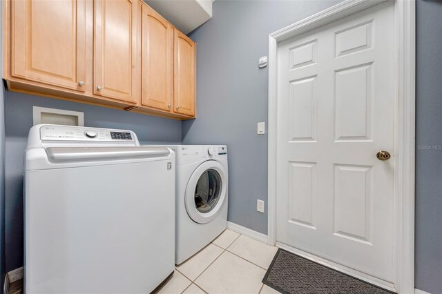 washroom with baseboards, washer and clothes dryer, light tile patterned floors, and cabinet space