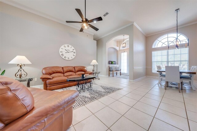 living room featuring visible vents, light tile patterned floors, arched walkways, crown molding, and baseboards