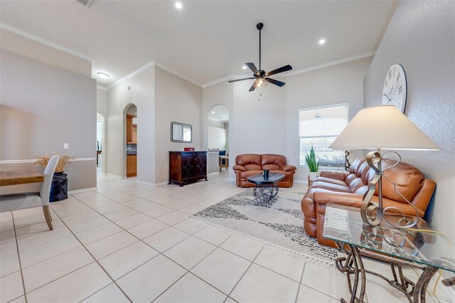 living area with light tile patterned flooring, arched walkways, ceiling fan, and crown molding