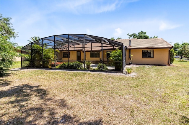 rear view of property with a lanai, a tiled roof, and a yard