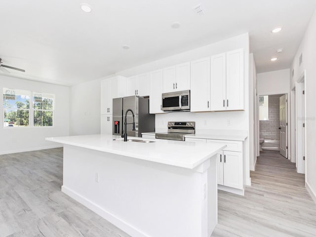 7744 Sun N Lake Blvd, Sebring, FL 33872 - kitchen with light wood-type flooring, stainless steel appliances, a kitchen island with sink, and a sink