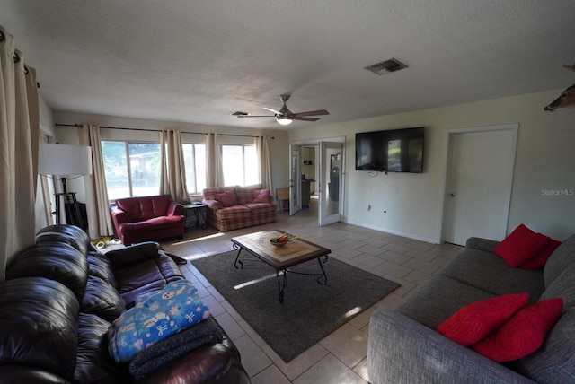 living room with a ceiling fan, visible vents, a textured ceiling, and light tile patterned floors