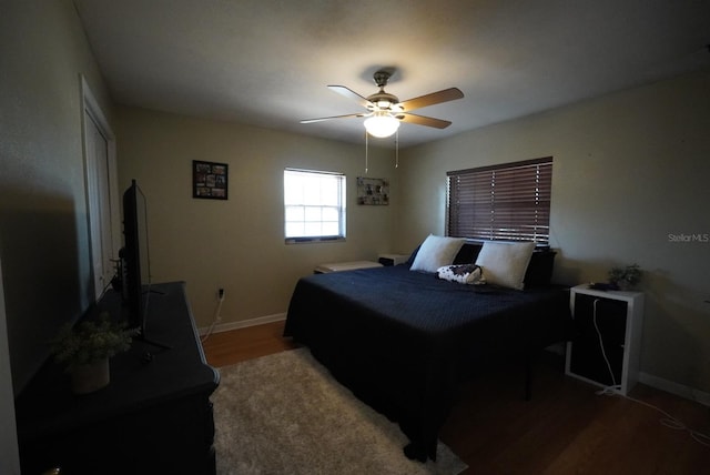 bedroom with ceiling fan, baseboards, wood finished floors, and a closet