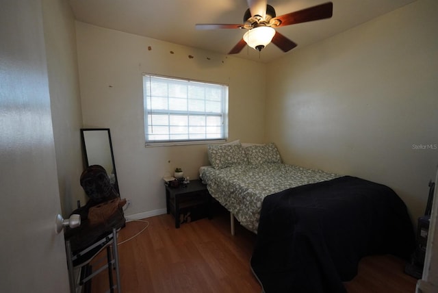 bedroom featuring baseboards, wood finished floors, and ceiling fan