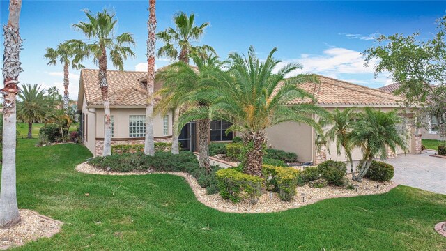 mediterranean / spanish-style house with a tiled roof, driveway, a front yard, and stucco siding