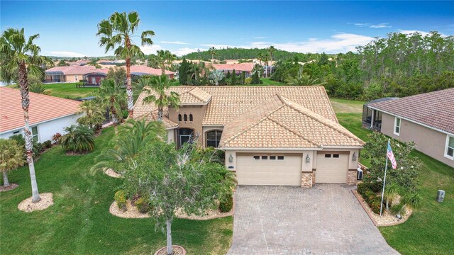 mediterranean / spanish home with an attached garage, driveway, a front yard, and stucco siding