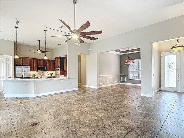 unfurnished living room with baseboards, a healthy amount of sunlight, and ceiling fan with notable chandelier
