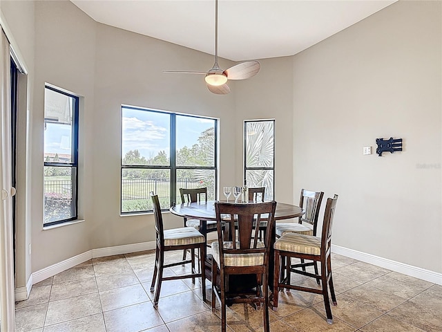 dining area with a ceiling fan, baseboards, light tile patterned floors, and high vaulted ceiling