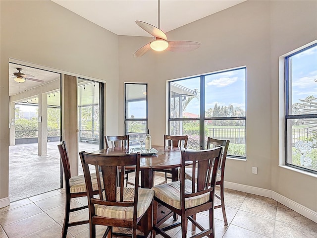 dining area featuring light tile patterned flooring, ceiling fan, baseboards, and high vaulted ceiling