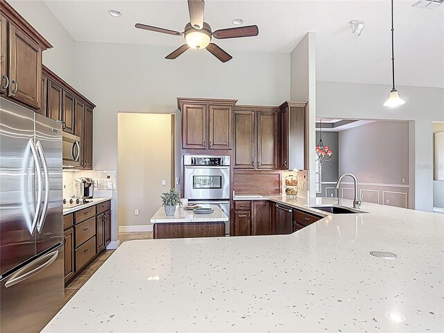 kitchen featuring ceiling fan, appliances with stainless steel finishes, light stone countertops, a sink, and backsplash