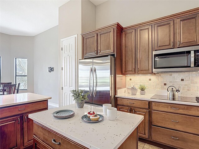 kitchen with backsplash, appliances with stainless steel finishes, a center island, and light countertops