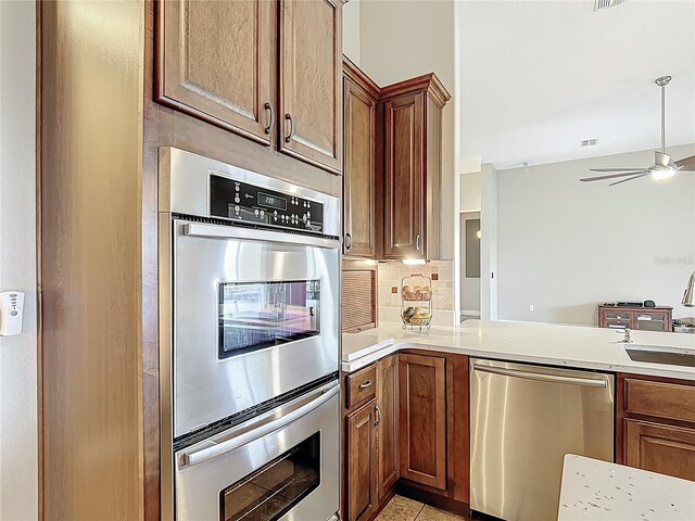kitchen featuring ceiling fan, a sink, light countertops, stainless steel appliances, and decorative backsplash