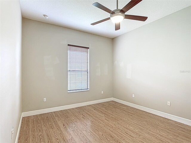 unfurnished room featuring light wood-style floors, a ceiling fan, baseboards, and a textured ceiling