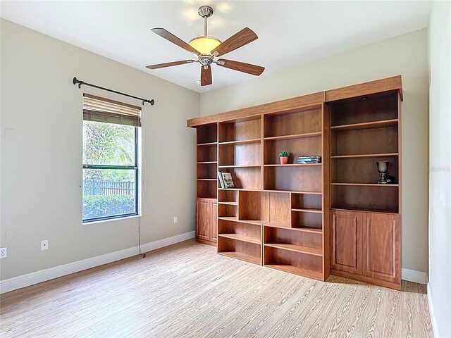 spare room featuring a ceiling fan, baseboards, and light wood-style flooring
