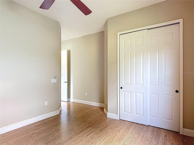 unfurnished bedroom featuring a closet, baseboards, ceiling fan, and light wood-type flooring