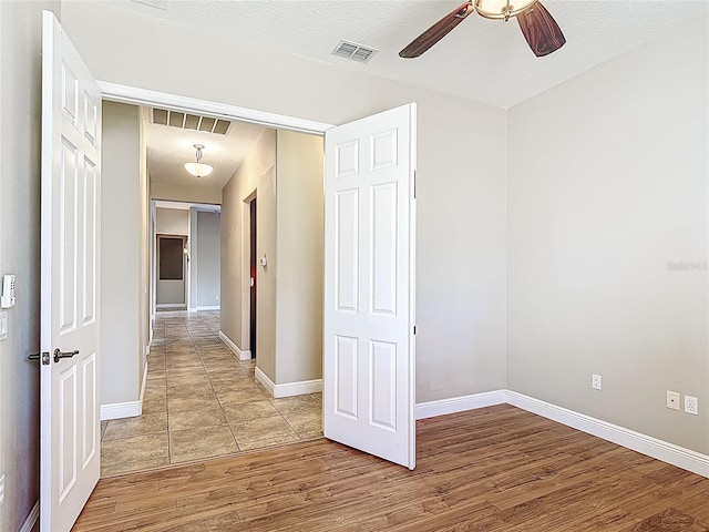 hallway featuring visible vents, baseboards, and light wood-type flooring