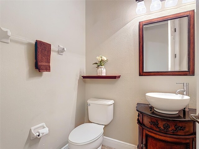 half bathroom featuring vanity, baseboards, and toilet