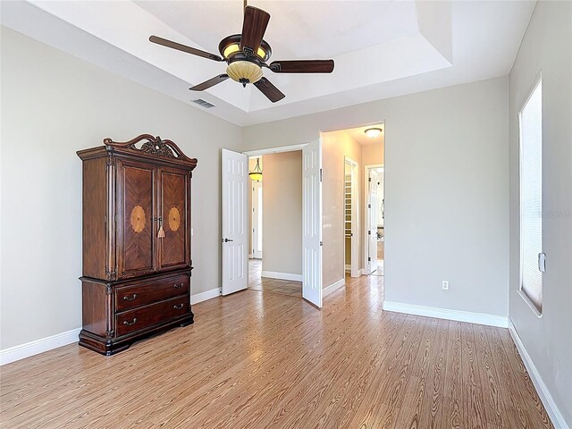 unfurnished bedroom featuring baseboards, multiple windows, light wood-style flooring, and visible vents