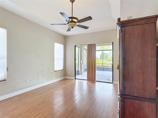 spare room featuring a ceiling fan, baseboards, visible vents, and light wood finished floors