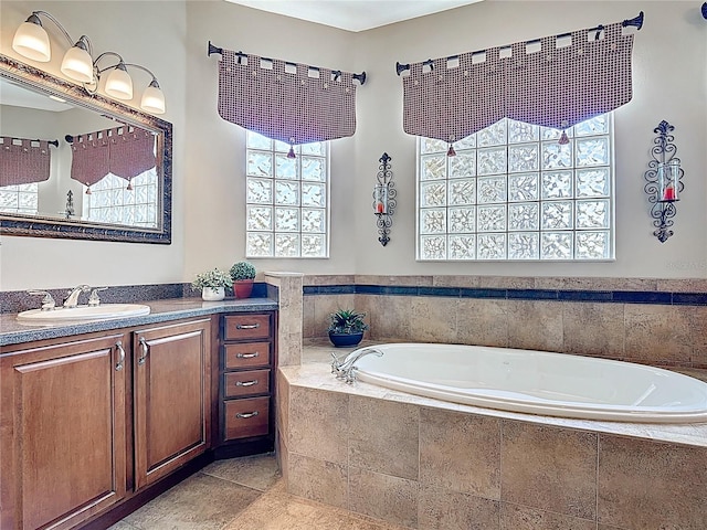 bathroom featuring tile patterned flooring, a healthy amount of sunlight, a garden tub, and vanity