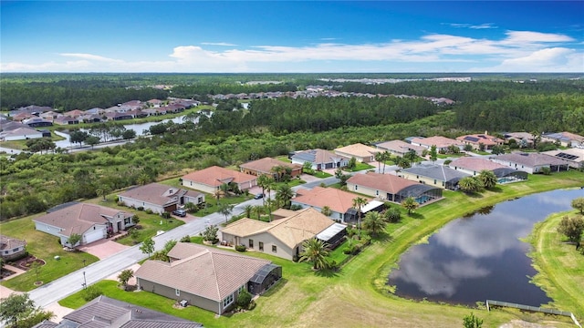drone / aerial view with a water view, a view of trees, and a residential view