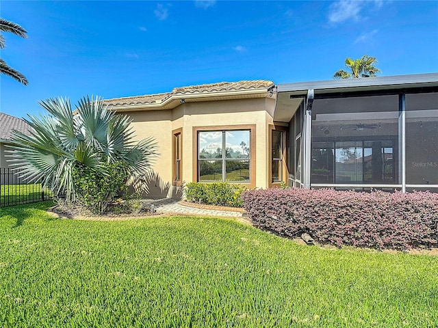 exterior space featuring a lawn, fence, stucco siding, and a tiled roof