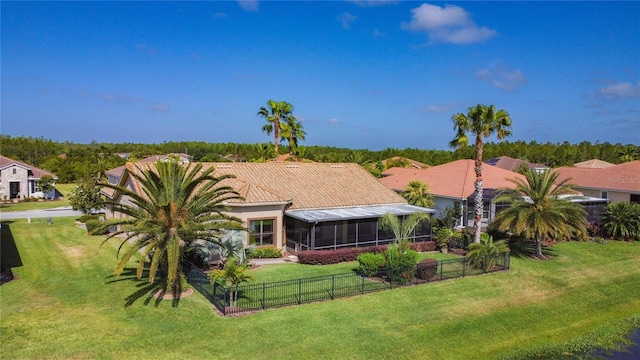 rear view of property with a yard, a tile roof, a fenced backyard, and a sunroom