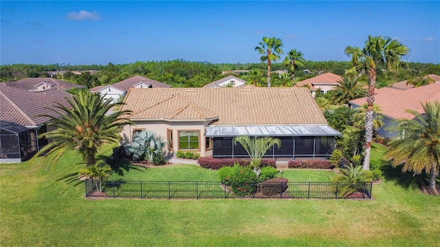 view of front of home featuring a sunroom, a fenced backyard, a front lawn, and a tiled roof