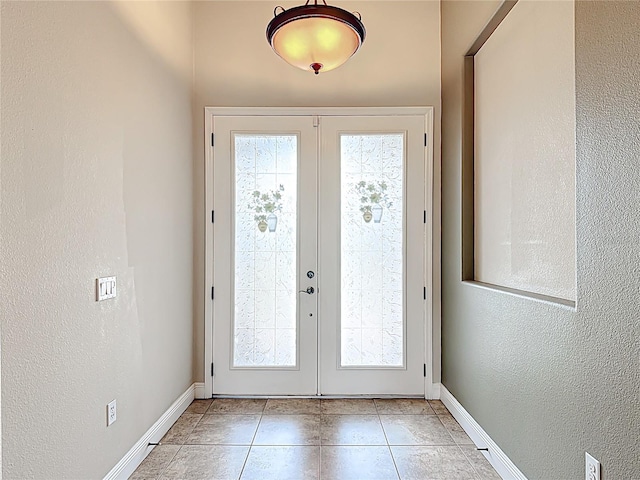 foyer featuring baseboards, a textured wall, and french doors