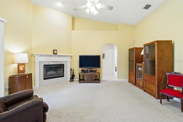 2374 Eagle Trace Dr, Kissimmee, FL 34746 - carpeted living area featuring visible vents, arched walkways, a tiled fireplace, a ceiling fan, and high vaulted ceiling