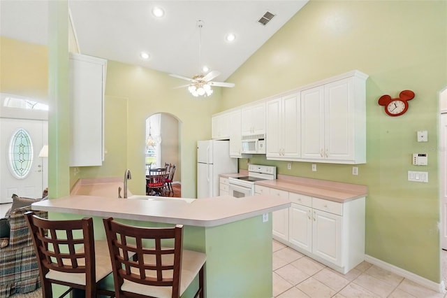 2374 Eagle Trace Dr, Kissimmee, FL 34746 - kitchen featuring white appliances, a breakfast bar area, visible vents, light countertops, and arched walkways