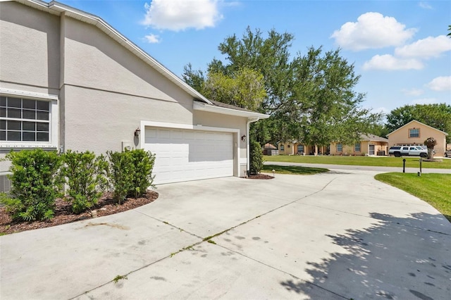 2374 Eagle Trace Dr, Kissimmee, FL 34746 - view of property exterior with driveway, a lawn, stucco siding, and an attached garage