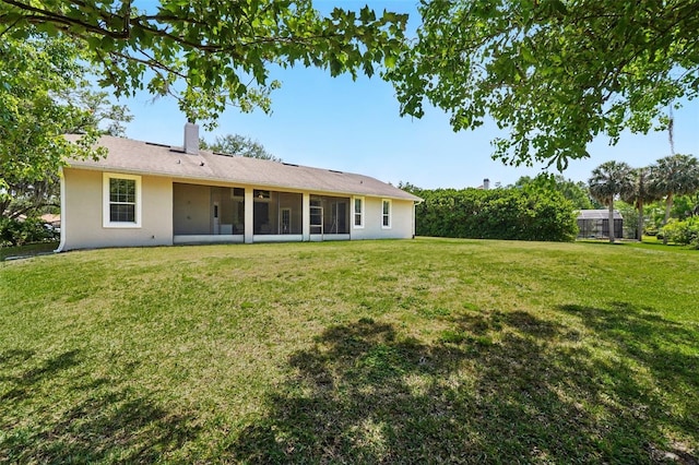 2374 Eagle Trace Dr, Kissimmee, FL 34746 - back of house with stucco siding, a chimney, a yard, and a sunroom