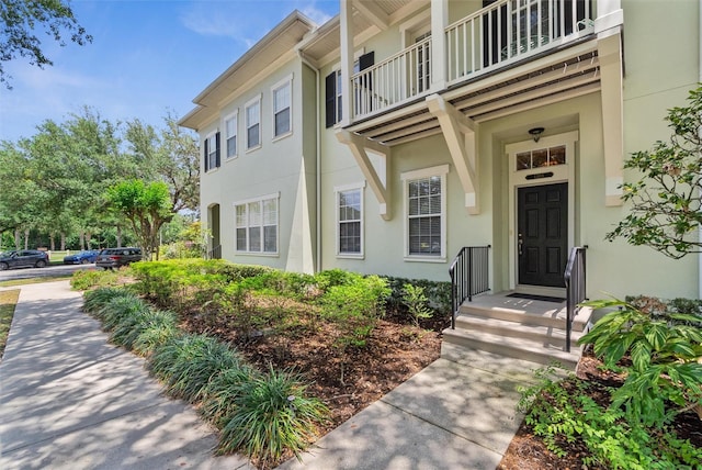 entrance to property with stucco siding and a balcony