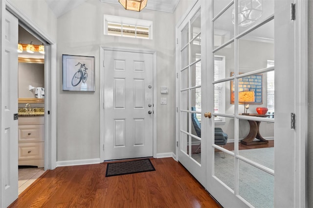 foyer entrance featuring baseboards, wood finished floors, french doors, and crown molding