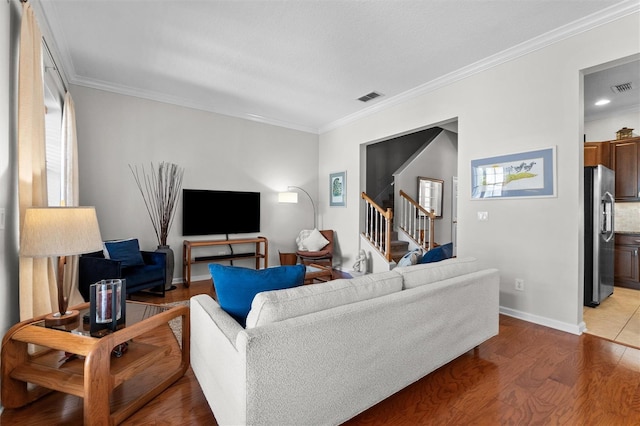 living area featuring ornamental molding, visible vents, stairway, and wood finished floors