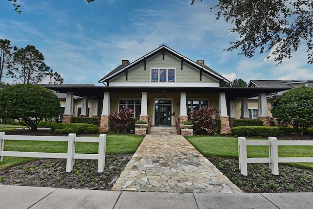 view of front of home featuring fence, a chimney, a porch, and a front lawn
