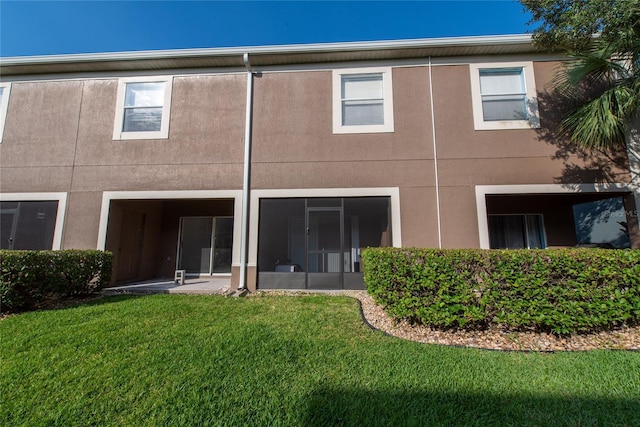rear view of property with stucco siding and a yard
