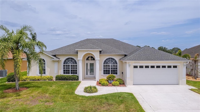 ranch-style house with driveway, roof with shingles, a front yard, stucco siding, and a garage
